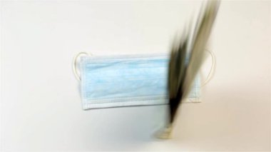 Bulaşıcı hastalıklara karşı tıbbi maske ve beyaz arka planda çok para.