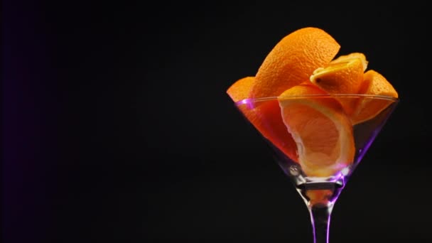 Pomarańcze Szklance Martini Obracają Się Czarnym Tle Fioletowym Odcieniu — Wideo stockowe