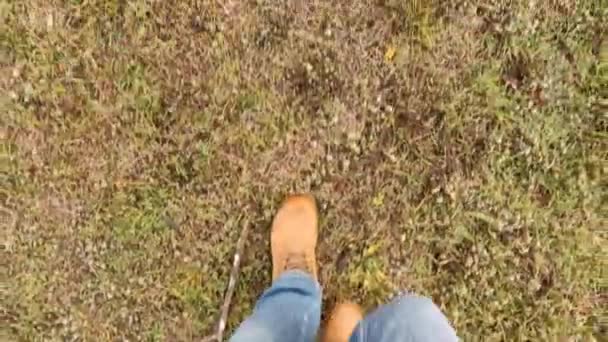 暖かい茶色のブーツの男が秋に緑の草の上を歩く — ストック動画