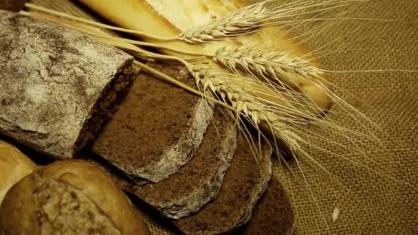 不同的新鲜面包卷和小穗麦片挨着一个古老的表面 — 图库视频影像