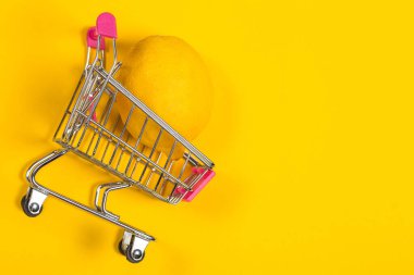 Sarı arka planda alışveriş arabasında sarı limon, alışveriş arabası.