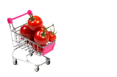 Beyaz arka planda kiraz domatesleri ve alışveriş arabası