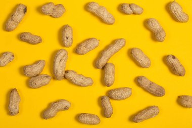 Peanuts in shell on yellow background, healthy food