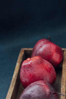 Koyu arkaplanda tahta bir kutuda kırmızı elmalar.