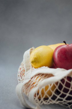 Sarı limon, kırmızı elma örgü çantada.