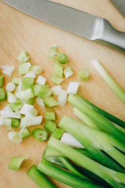 sliced green onions on wooden cutting board and parsley
