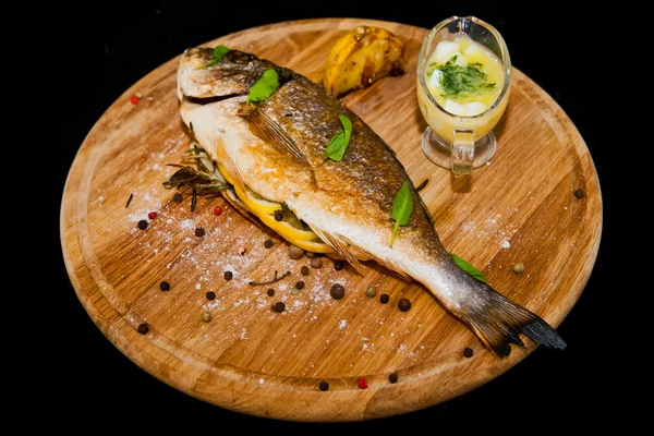 Peixe grelhado com limão e especiarias em uma tábua de madeira — Fotografia de Stock