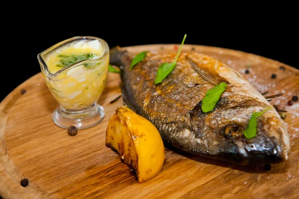 Peixe grelhado com limão e especiarias em uma tábua de madeira — Fotografia de Stock