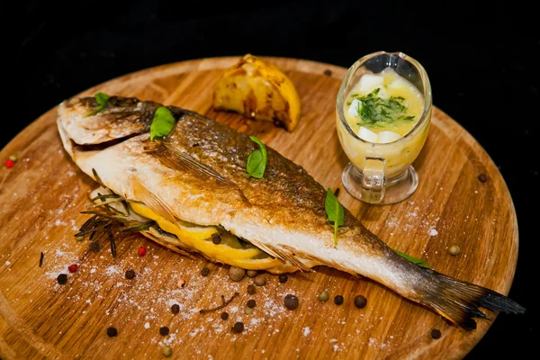 Grilled fish with lemon and spices on a wooden board — Stock Photo, Image