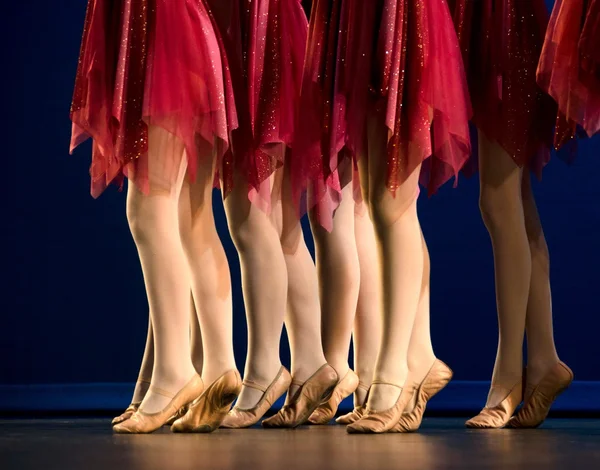 Legs of a group of ballerinas in red skirts — Stock Photo, Image