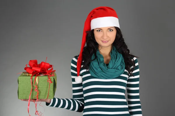 Girl in santa hat and striped dress with gift — Stock Photo, Image