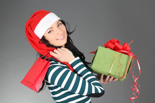 Vrouw in kerstmuts met een geschenk en zak — Stockfoto