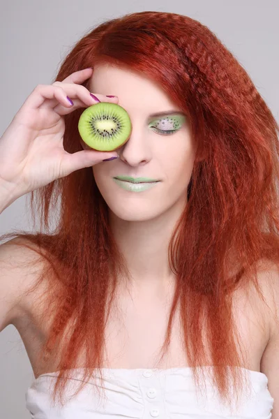 Woman holding kiwi fruit for her eye — Stock Photo, Image