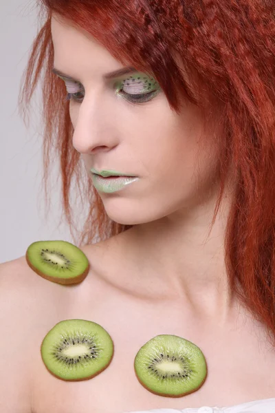 Flicka med kiwi skivor på hennes hud — Stockfoto