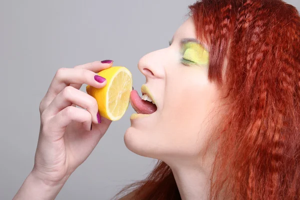 Rödhårig tjej slickar citron — Stockfoto