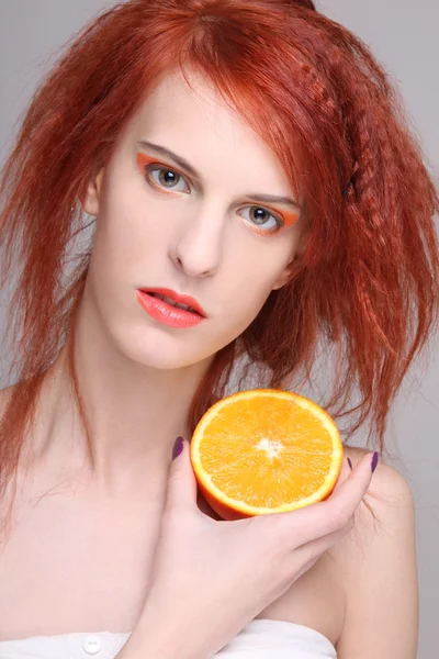 Redhaired woman with orange half in her hand — Stock Photo, Image