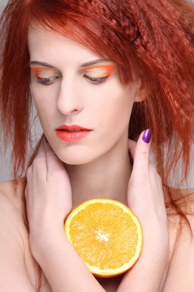 Porträtt av rödhårig kvinna med orange halv — Stockfoto