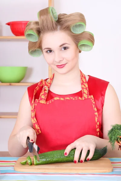 Attractive housewife cutting cucumber in the kitchen — Stock Photo, Image