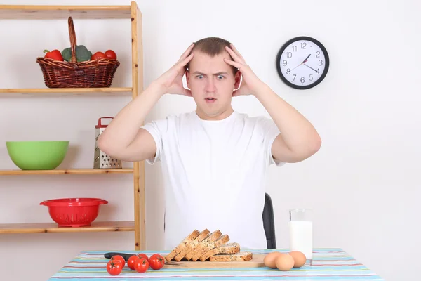 Shocked man sitting in the kitchen — Stock Photo, Image