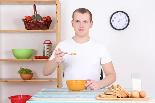 Homem comendo cereal com leite na cozinha — Fotografia de Stock