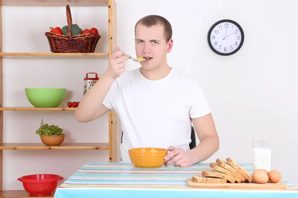 Hombre comiendo hojuelas de maíz con leche en la cocina —  Fotos de Stock