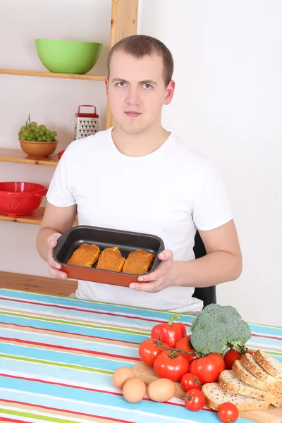 Young man cooking meat in the kitchen — Stock Photo, Image