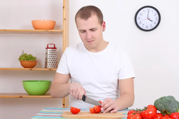 Husband cutting tomato in the kitchen — Stock Photo, Image