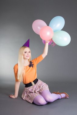 Balonlar ile gri oturan genç güzel sarışın