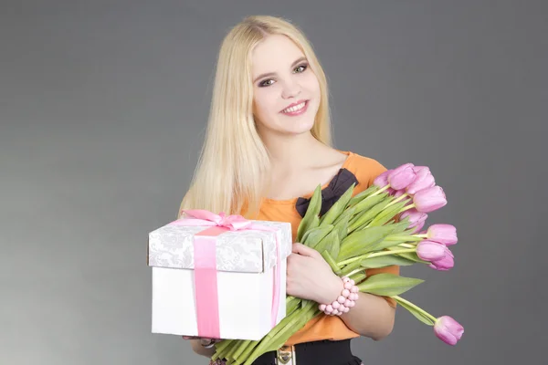 Portrait of beautiful blondie girl with gift and tulips — Stock Photo, Image