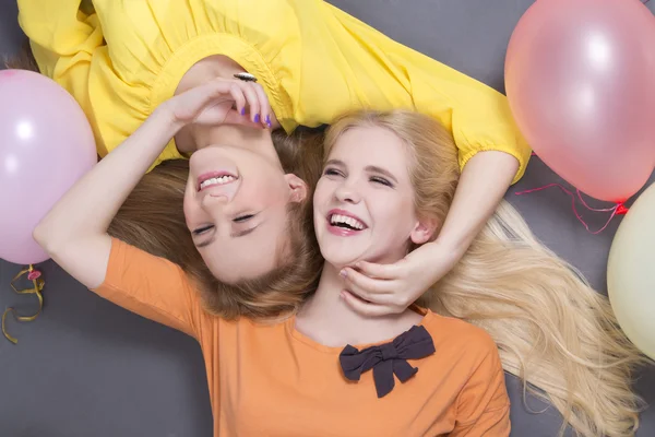 Smiling teenage girls lying with colorful balloons — Stock Photo, Image