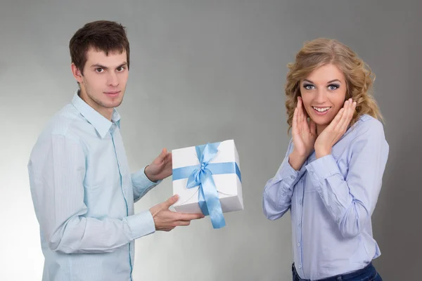 Young man with gift and surprised girlfriend — Stock Photo, Image