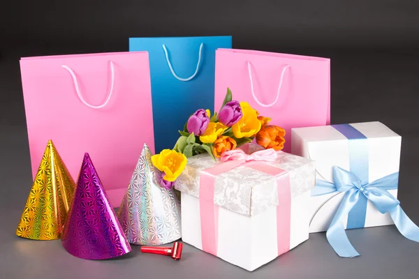 Composizione di tulipani, scatole regalo e cappelli birtday sopra grigio — Foto Stock