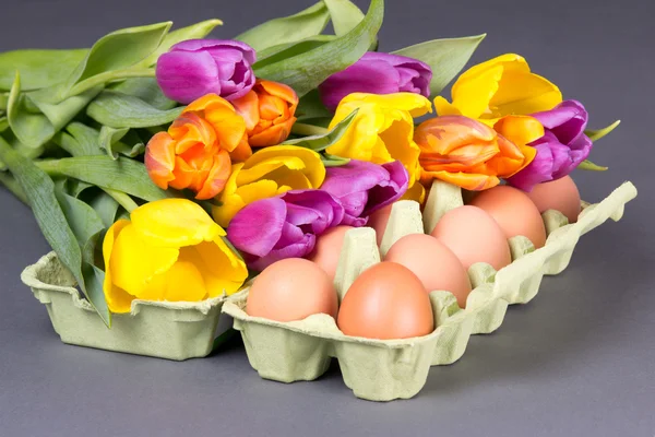 Bouquet of tulip flowers and eggs on grey — Stock Photo, Image