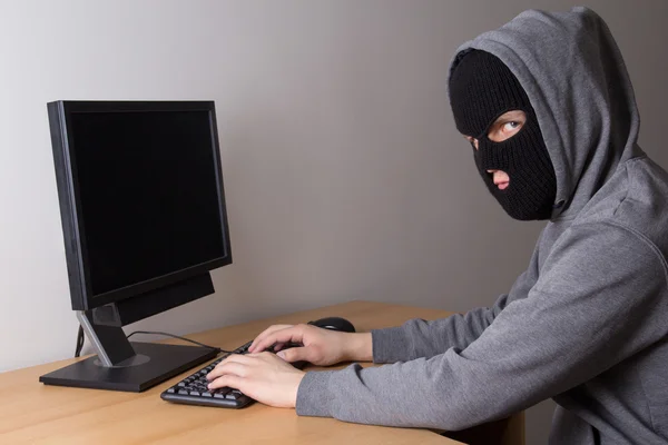 Jóvenes enmascarado hacker usando un pc — Foto de Stock