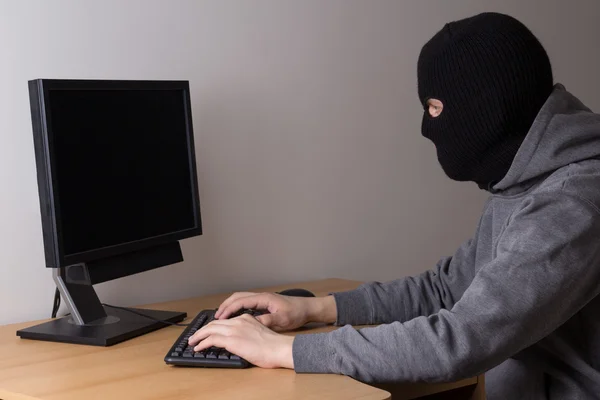 Человек в маске с компьютером в офисе — стоковое фото