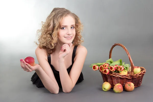 Joven rubia acostada con las manzanas y las flores — Foto de Stock