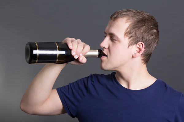 Young man drinking champagne over grey — Stock Photo, Image