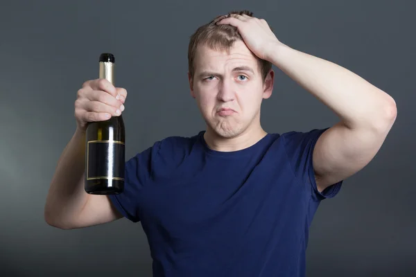 Uomo ubriaco con la bottiglia di champagne sul grigio — Foto Stock