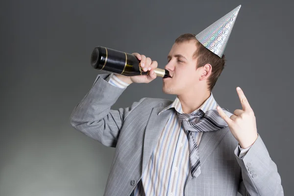 Młody biznesmen picia szampana na szarym tle — Zdjęcie stockowe