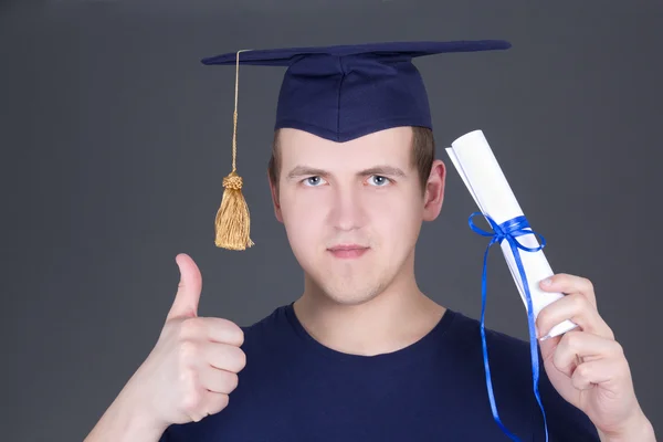 Jonge afstuderen man duimschroef opwaarts over grijs — Stockfoto