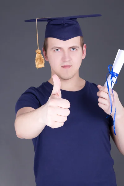 Happy graduation man with diploma thumbs up over grey — Stock Photo, Image