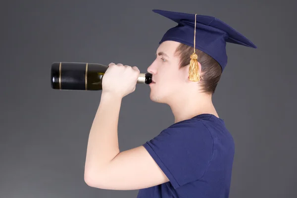 Выпускной человек пьет шампанское над серый — стоковое фото