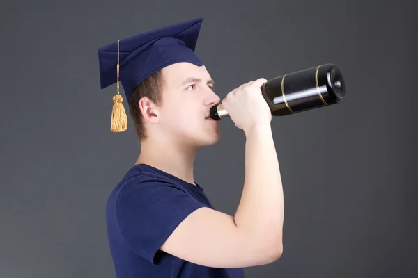 Jonge afstuderen man drinken champagne over grijs — Stockfoto