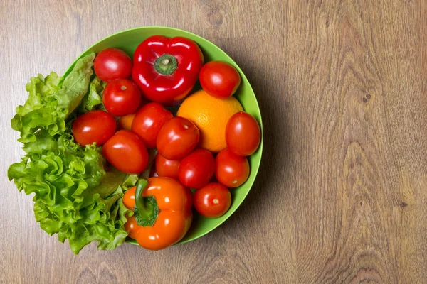 Čerstvá rajčata, papriky a salát na dřevěný stůl — Stock fotografie