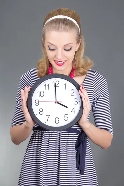 Dreaming pinup girl in striped dress with clock over grey — Stock Photo, Image