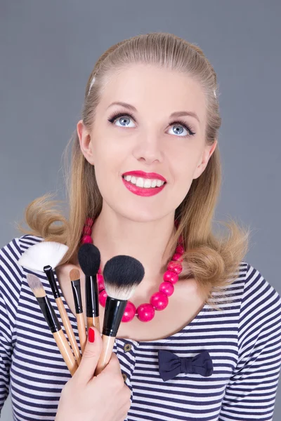 Young dreaming pinup woman with make up brushes — Stock Photo, Image