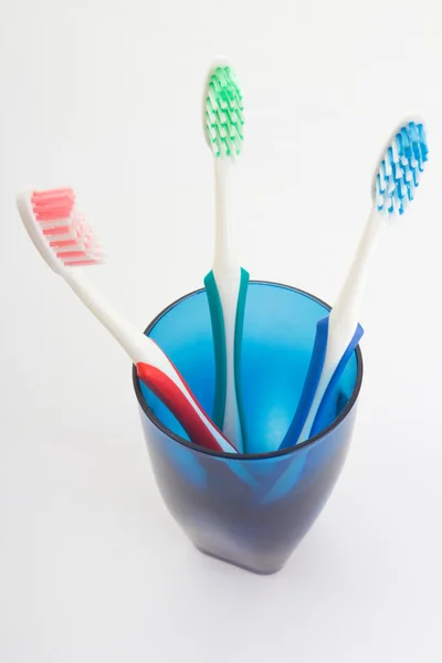 Escovas de dente em vidro azul sobre branco — Fotografia de Stock