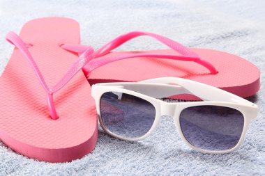 Kırmızı flip flop ve havlu üzerinde güneş gözlüğü
