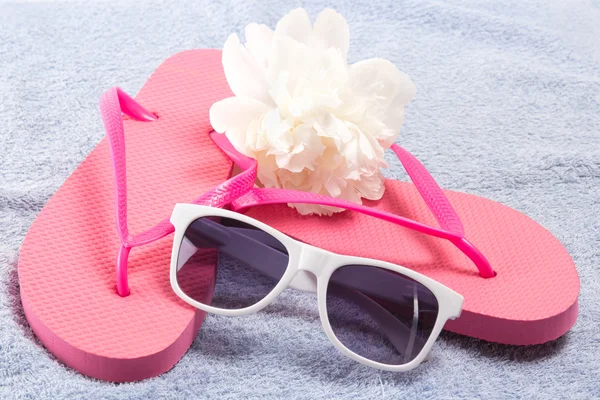 Red flip flops, sunglasses and flower over towel — Stock Photo, Image