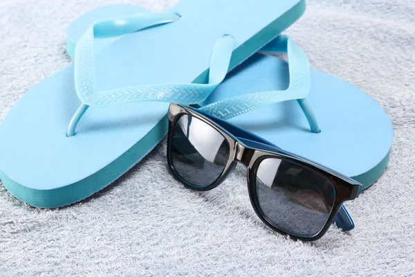 Flip flops and sunglasses over towel — Stock Photo, Image